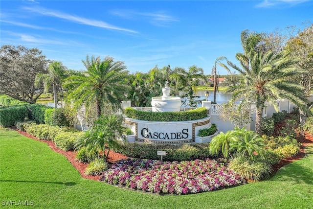 community / neighborhood sign featuring a water view and a lawn