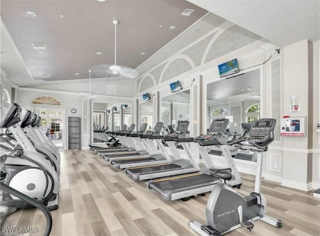 gym with a high ceiling, crown molding, and light hardwood / wood-style flooring