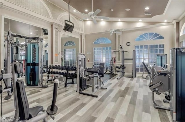 gym featuring a towering ceiling, wood-type flooring, and ceiling fan