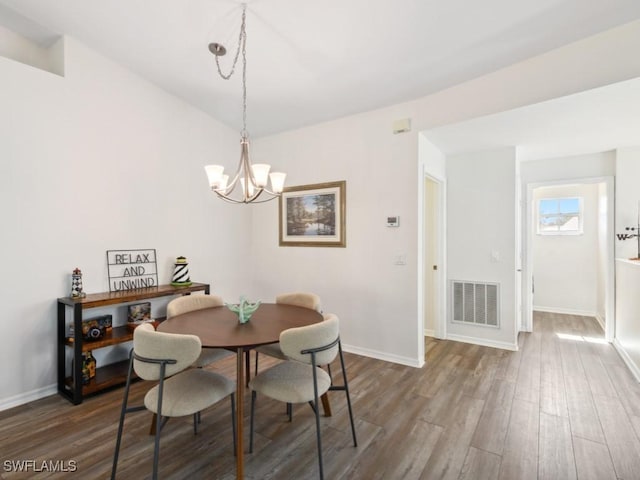 dining space with hardwood / wood-style floors and a notable chandelier