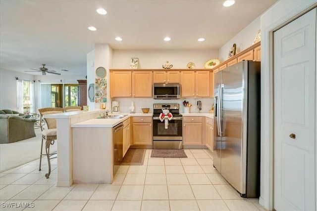 kitchen with sink, a kitchen bar, kitchen peninsula, stainless steel appliances, and light brown cabinets