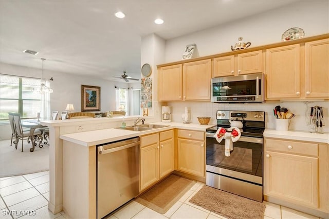 kitchen with appliances with stainless steel finishes, sink, light brown cabinets, and kitchen peninsula