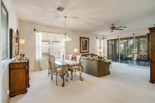 carpeted dining space featuring ceiling fan with notable chandelier