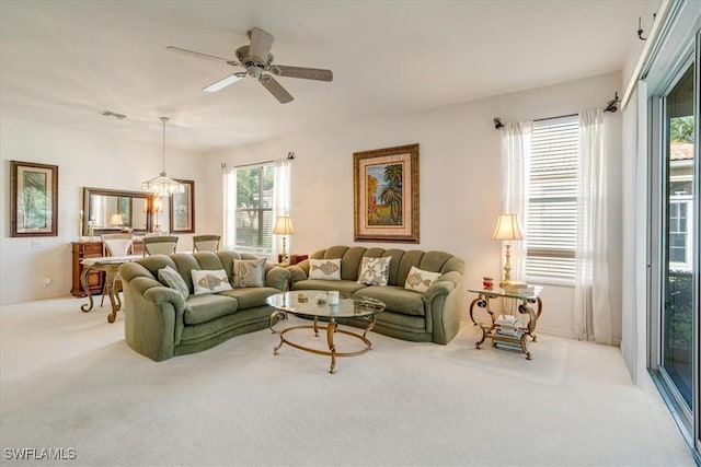 carpeted living room featuring plenty of natural light and ceiling fan with notable chandelier