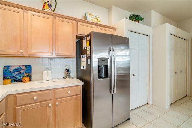 kitchen with light tile patterned flooring, stainless steel fridge with ice dispenser, decorative backsplash, and light brown cabinets