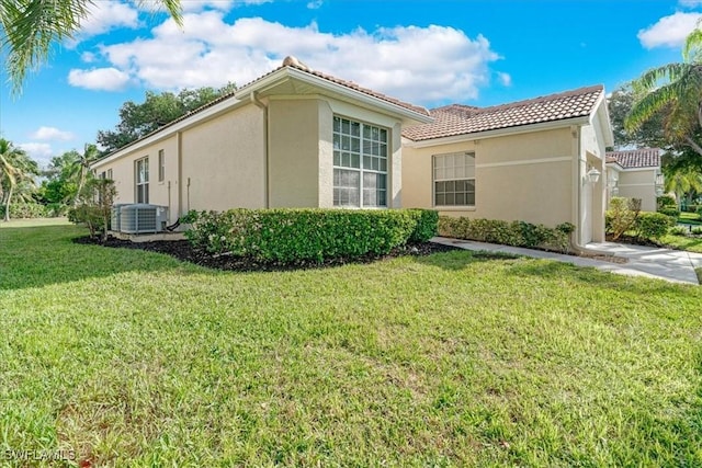 view of side of property featuring a yard and central air condition unit