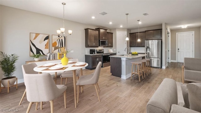 dining space with an inviting chandelier, light hardwood / wood-style floors, and sink