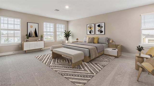 carpeted bedroom with visible vents, multiple windows, and baseboards