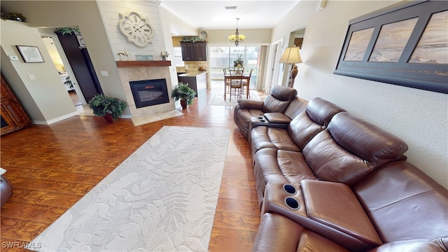 living room featuring dark hardwood / wood-style flooring, a notable chandelier, and a tile fireplace