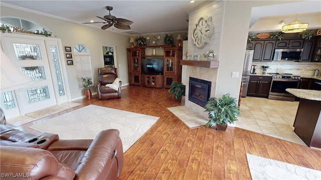 living room with crown molding, ceiling fan, and light hardwood / wood-style floors