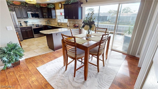 kitchen with sink, backsplash, dark brown cabinetry, kitchen peninsula, and stainless steel appliances