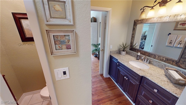 bathroom with hardwood / wood-style flooring, vanity, and toilet