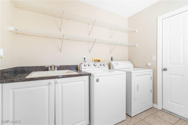 clothes washing area featuring sink, light tile patterned floors, cabinets, and washer and dryer