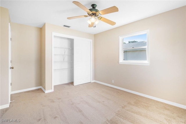 unfurnished bedroom with ceiling fan, light carpet, and a closet