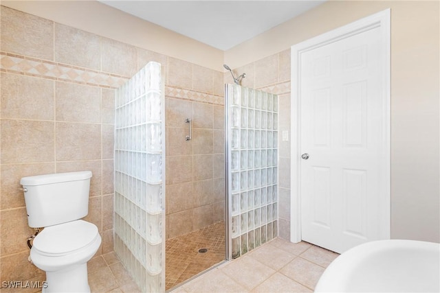 bathroom with tile patterned floors, toilet, tile walls, and a tile shower