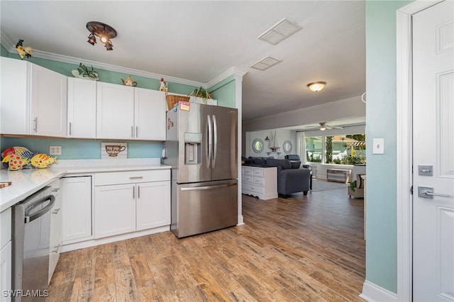 kitchen with appliances with stainless steel finishes, white cabinets, ceiling fan, light hardwood / wood-style floors, and crown molding