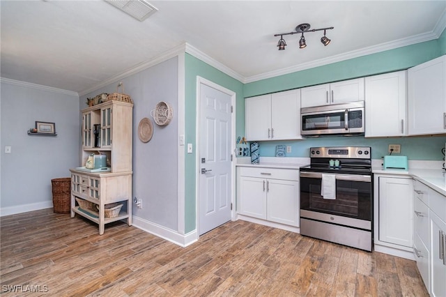 kitchen with white cabinetry, stainless steel appliances, crown molding, and light hardwood / wood-style flooring