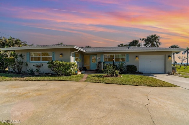 ranch-style home with a garage and a lawn