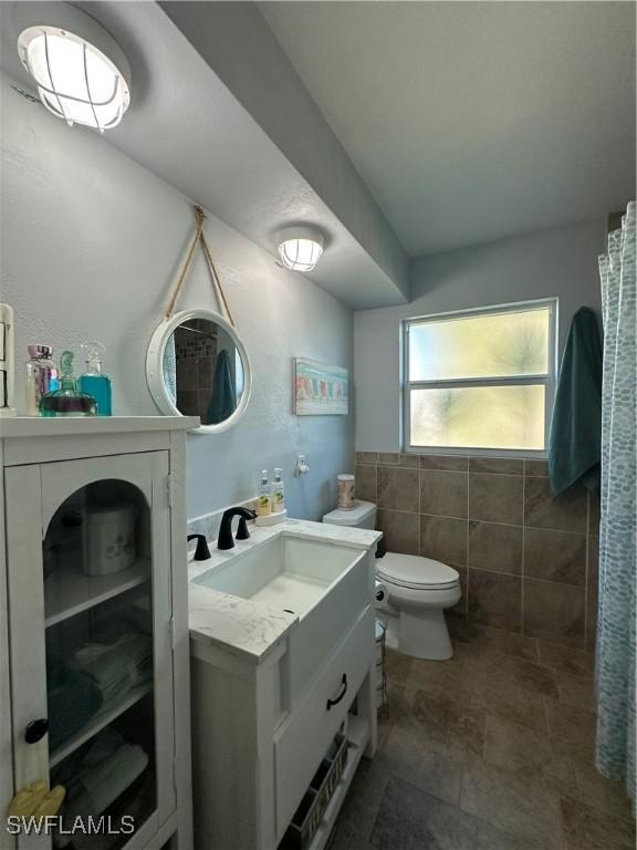 bathroom featuring vanity, tile walls, and toilet