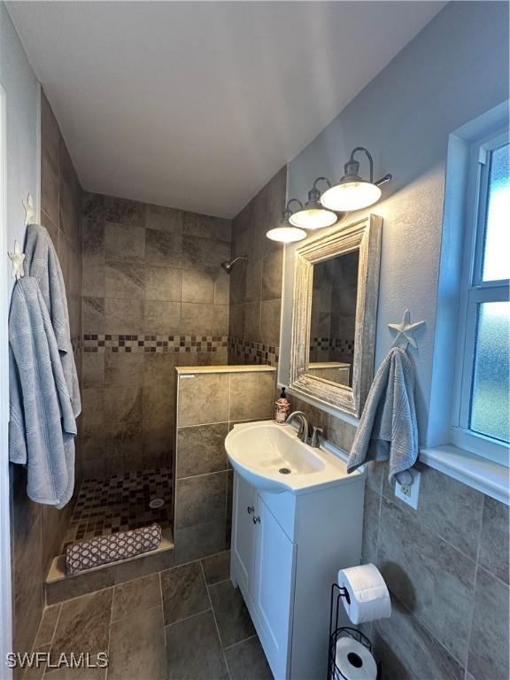 bathroom with vanity, tiled shower, and tile walls