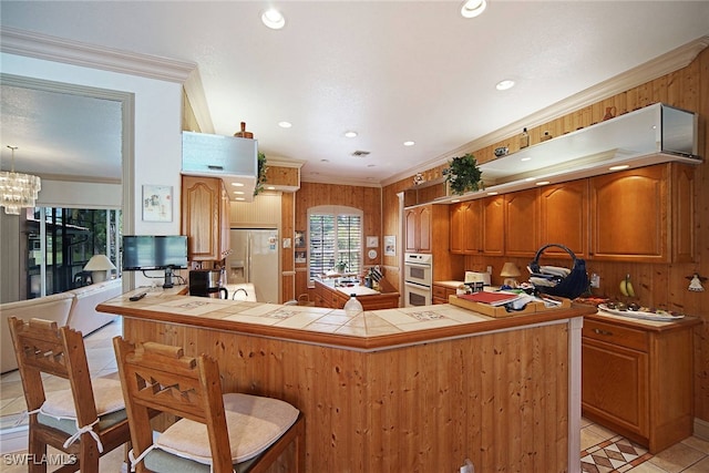 kitchen featuring fridge with ice dispenser, crown molding, tile countertops, kitchen peninsula, and double oven