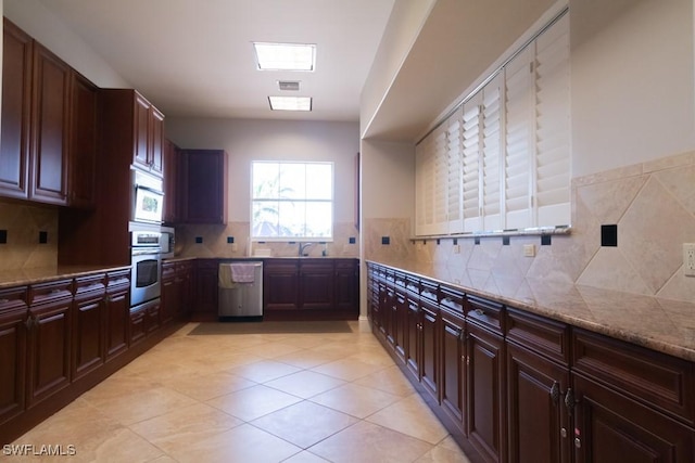 kitchen featuring sink, tasteful backsplash, light stone counters, light tile patterned floors, and stainless steel appliances