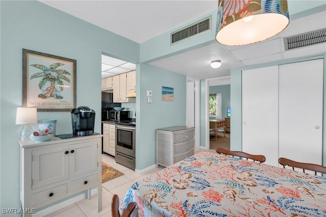 bedroom featuring a drop ceiling, light tile patterned floors, and a closet