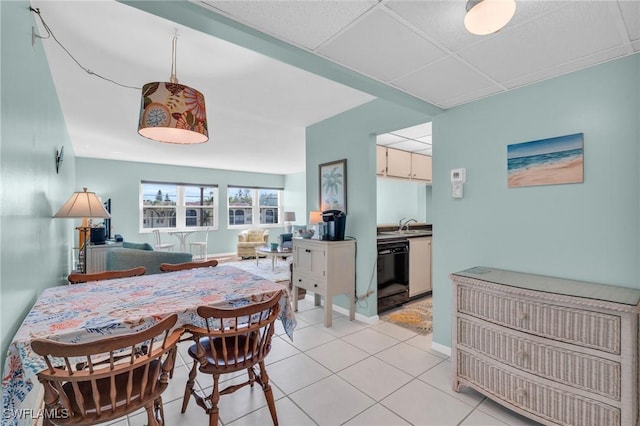 tiled dining space with sink and a drop ceiling