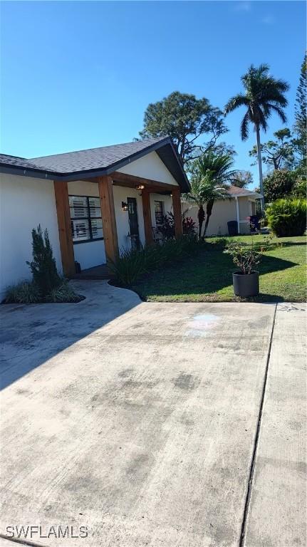 view of front of house featuring driveway, a front lawn, and stucco siding