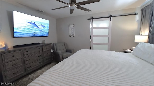 carpeted bedroom featuring ceiling fan and a barn door