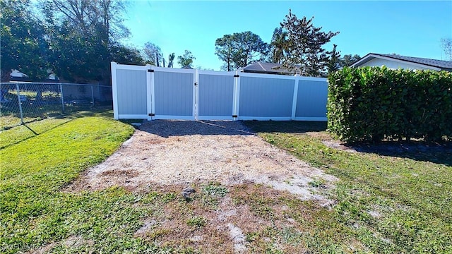 view of gate with a yard and fence