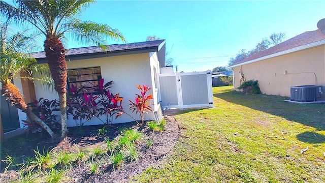 view of side of property featuring central air condition unit, a lawn, fence, and stucco siding