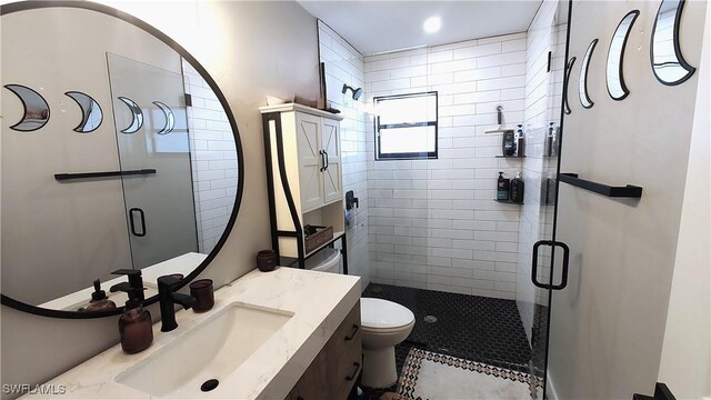 bathroom featuring vanity, a shower with door, and toilet