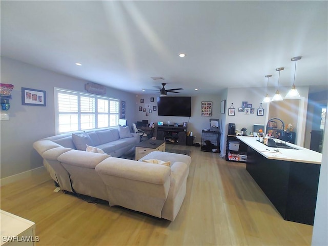 living room with light wood-style flooring, a ceiling fan, and recessed lighting