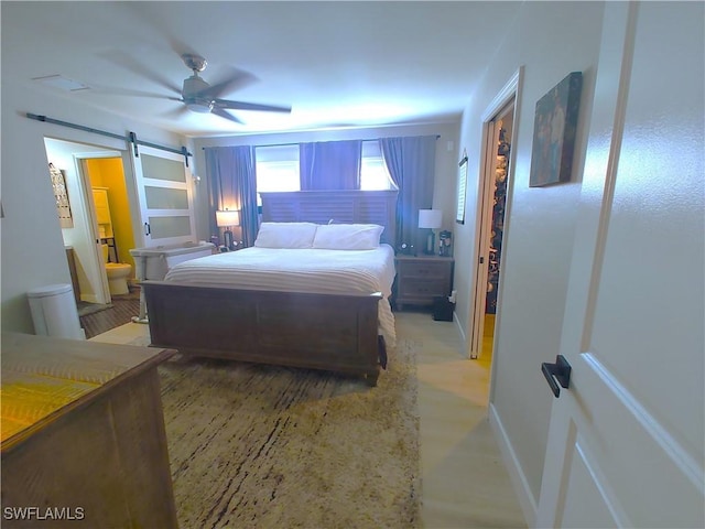 bedroom with ceiling fan, a barn door, ensuite bath, and baseboards