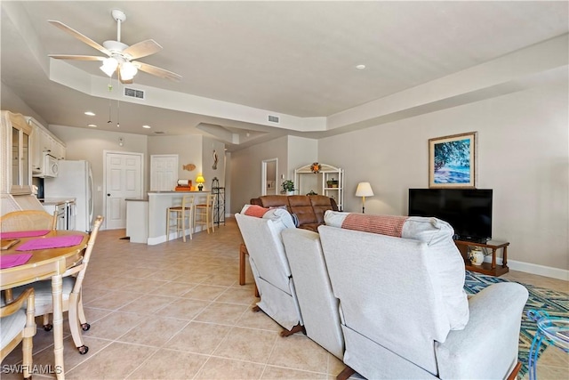 tiled living room featuring a tray ceiling and ceiling fan