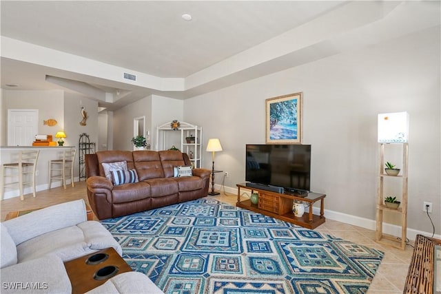 living room with tile patterned floors and a tray ceiling