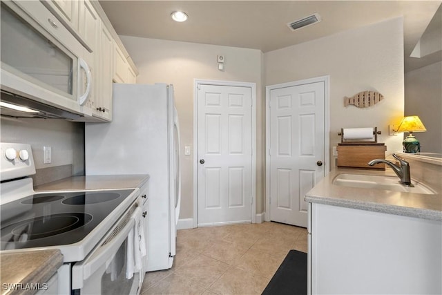 kitchen featuring sink, light tile patterned floors, white cabinets, and white appliances