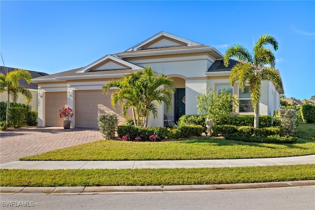 view of front of home with a garage, decorative driveway, a front lawn, and stucco siding