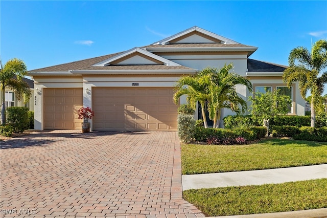 view of front facade featuring a garage, decorative driveway, stucco siding, and a front yard