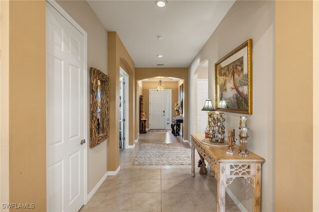 hall featuring arched walkways, light tile patterned flooring, baseboards, and recessed lighting