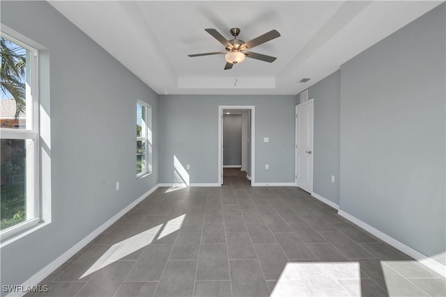 tiled spare room with a raised ceiling and ceiling fan