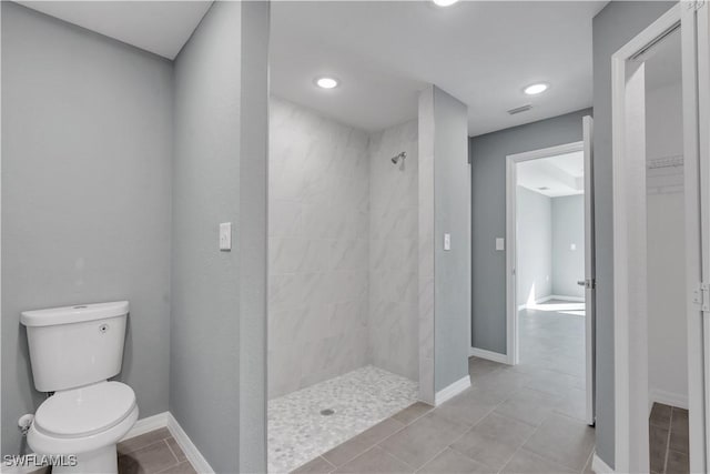 bathroom featuring toilet, tile patterned flooring, and a tile shower