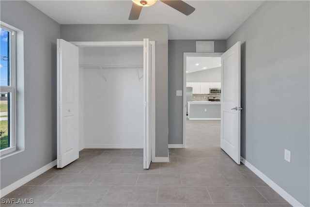 unfurnished bedroom featuring light tile patterned floors, ceiling fan, and a closet