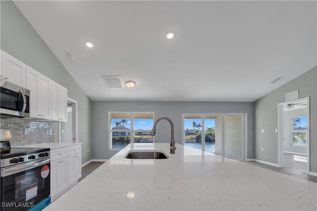 kitchen featuring sink, light stone counters, white cabinetry, appliances with stainless steel finishes, and decorative backsplash