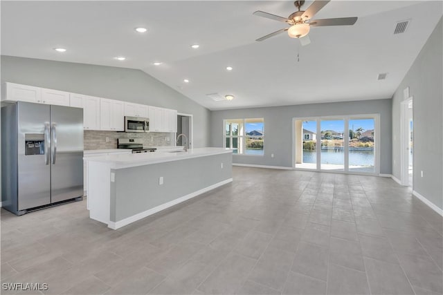 kitchen with sink, a water view, appliances with stainless steel finishes, a kitchen island with sink, and white cabinets