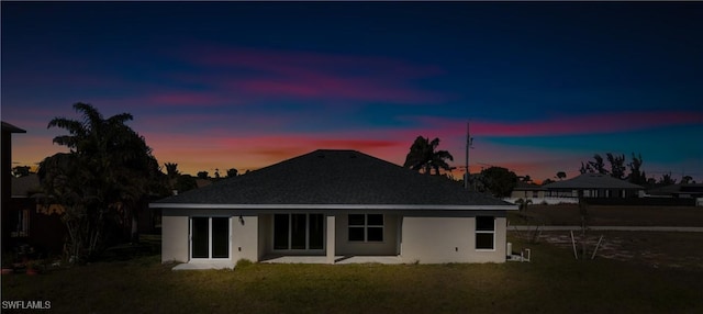 back house at dusk featuring a patio area