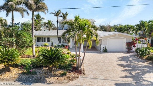 ranch-style house with a garage, decorative driveway, and stucco siding