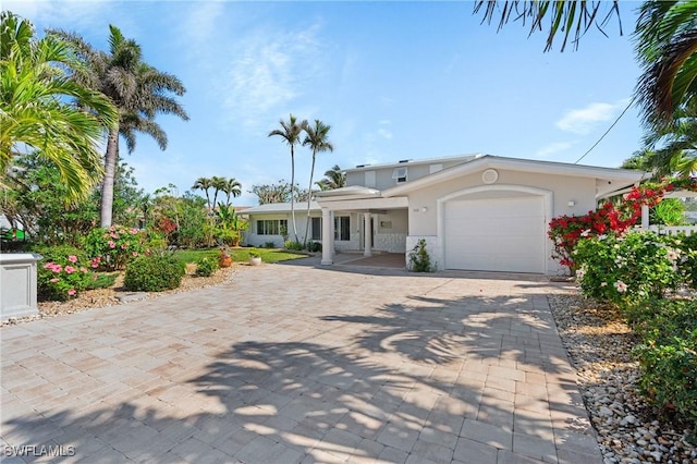 view of front of house with an attached garage, decorative driveway, and stucco siding