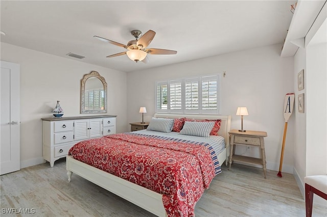 bedroom featuring ceiling fan, light wood-style flooring, visible vents, and baseboards